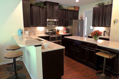 Inspiration for a kitchen remodel in Other with a single-bowl sink, raised-panel cabinets, black cabinets, quartzite countertops, porcelain backsplash, stainless steel appliances and an island