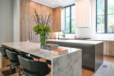 Open concept kitchen - large modern galley light wood floor open concept kitchen idea in Atlanta with an undermount sink, flat-panel cabinets, light wood cabinets, quartzite countertops, beige backsplash, quartz backsplash, stainless steel appliances, two islands and beige countertops