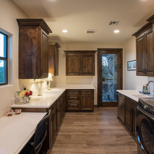 This is an example of a large country u-shaped utility room in Phoenix with a submerged sink, raised-panel cabinets, dark wood cabinets, engineered stone countertops, beige walls, medium hardwood flooring, a side by side washer and dryer, brown floors and turquoise worktops.