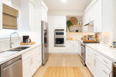 Example of a mid-sized minimalist galley beige floor enclosed kitchen design in Orange County with a drop-in sink, white cabinets, white backsplash, white appliances, no island, white countertops and quartz countertops