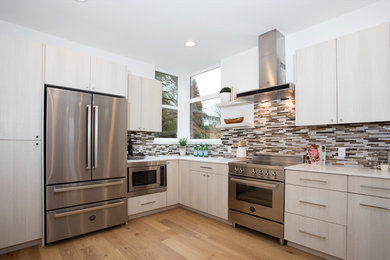 Example of a mid-sized minimalist u-shaped medium tone wood floor and brown floor eat-in kitchen design in Seattle with a single-bowl sink, flat-panel cabinets, light wood cabinets, quartz countertops, multicolored backsplash, mosaic tile backsplash, stainless steel appliances and a peninsula