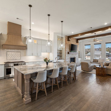 Open-concept great room with dark wood ceiling beams and brick fireplace