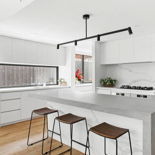 Design ideas for a contemporary l-shaped kitchen in Melbourne with an undermount sink, flat-panel cabinets, white cabinets, medium hardwood floors, with island, brown floor and grey benchtop.