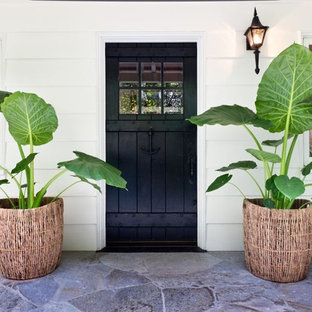 ロサンゼルスの片開きドアトロピカルスタイルのおしゃれな玄関ドア (黒いドア) の写真