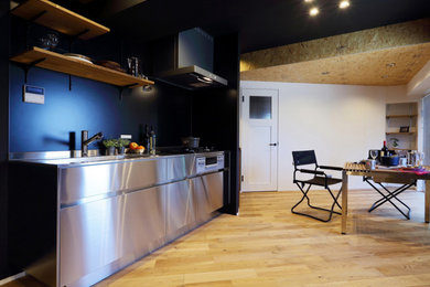 Foto de cocina lineal rústica abierta con encimera de acero inoxidable, suelo de madera en tonos medios, una isla, suelo beige y papel pintado