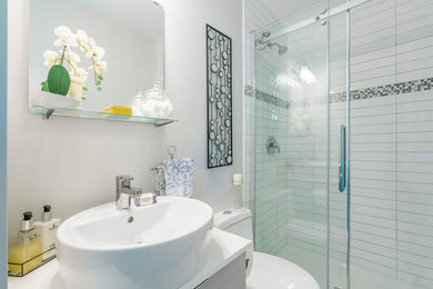 Small trendy 3/4 white tile and subway tile bathroom photo in Vancouver with flat-panel cabinets, white cabinets, a one-piece toilet, white walls, a vessel sink and solid surface countertops