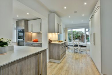 Medium sized modern u-shaped open plan kitchen in Other with a submerged sink, flat-panel cabinets, dark wood cabinets, laminate countertops, grey splashback, black appliances, lino flooring, no island, brown floors and grey worktops.