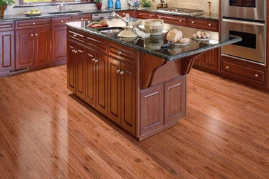 Mid-sized elegant l-shaped dark wood floor and brown floor kitchen photo in Miami with raised-panel cabinets, dark wood cabinets, granite countertops, beige backsplash, ceramic backsplash, stainless steel appliances and an island