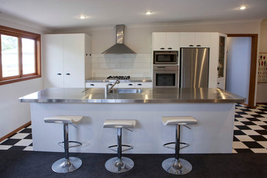 This is an example of a traditional eat-in kitchen in Wellington with an integrated sink, stainless steel benchtops, stainless steel appliances and with island.