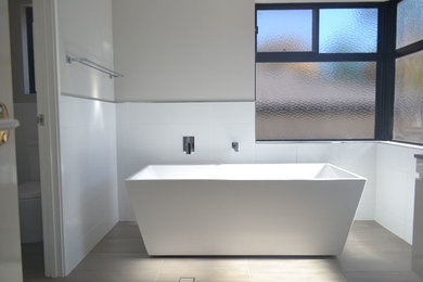 Inspiration for a contemporary bathroom in Perth with a freestanding tub, white tile, a drop-in sink and beige walls.