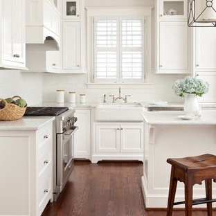 Traditional kitchen pantry ideas - Elegant l-shaped medium tone wood floor kitchen pantry photo in Richmond with a farmhouse sink, shaker cabinets, white cabinets, marble countertops, white backsplash, subway tile backsplash, stainless steel appliances and an island