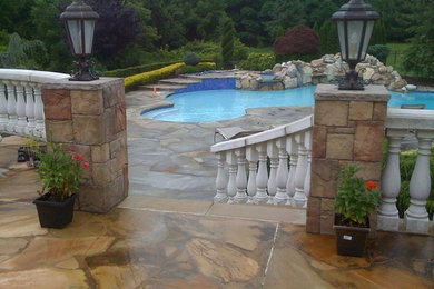 Design ideas for a mid-sized traditional backyard custom-shaped lap pool in New York with a hot tub and natural stone pavers.