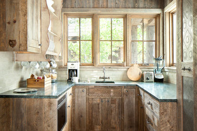 Inspiration for a small rustic u-shaped cement tile floor kitchen remodel in Orange County with an undermount sink, flat-panel cabinets, distressed cabinets, solid surface countertops, white backsplash, ceramic backsplash and no island