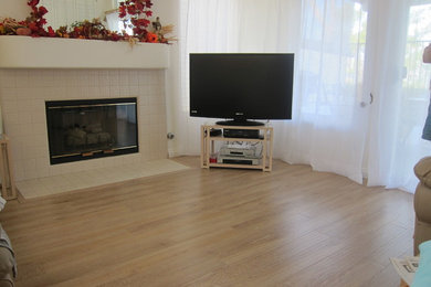 Photo of a mid-sized transitional formal enclosed living room in Los Angeles with white walls, light hardwood floors, a standard fireplace, a tile fireplace surround and a freestanding tv.