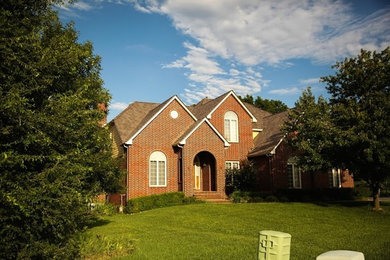 Large transitional two-storey brick beige house exterior in Wichita with a gable roof and a shingle roof.