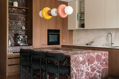 Inspiration for a large contemporary l-shaped open plan kitchen in Glasgow with flat-panel cabinets, marble worktops, beige splashback, black appliances, dark hardwood flooring, an island, brown floors, multicoloured worktops, feature lighting, a submerged sink, medium wood cabinets and stone slab splashback.