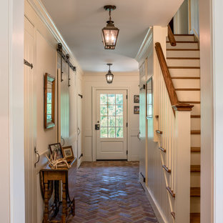 Bild på en stor vintage hall, med beige väggar, tegelgolv och rött golv