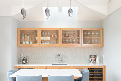 Inspiration for a transitional single-wall medium tone wood floor seated home bar remodel in Denver with an undermount sink, glass-front cabinets, light wood cabinets, quartz countertops and white countertops