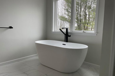 Modelo de cuarto de baño principal contemporáneo con bañera exenta, paredes beige, suelo de baldosas de porcelana y suelo blanco