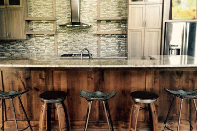 Example of a mid-sized trendy medium tone wood floor and brown floor kitchen design in Other with shaker cabinets, medium tone wood cabinets, granite countertops, metallic backsplash, matchstick tile backsplash, stainless steel appliances and an island