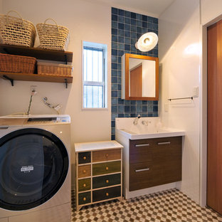 他の地域のアジアンスタイルのおしゃれなランドリールーム (フラットパネル扉のキャビネット、濃色木目調キャビネット、白い壁、マルチカラーの床) の写真