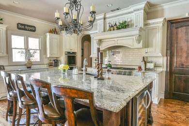 Example of a large transitional medium tone wood floor open concept kitchen design in Dallas with an undermount sink, raised-panel cabinets, beige cabinets, granite countertops, white backsplash, subway tile backsplash, stainless steel appliances and an island