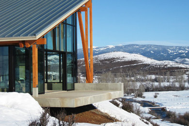 Example of a huge minimalist one-story glass house exterior design in Boise with a shed roof and a metal roof