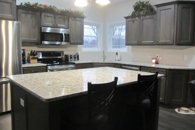 Inspiration for a mid-sized transitional l-shaped medium tone wood floor and gray floor open concept kitchen remodel in Other with an undermount sink, flat-panel cabinets, gray cabinets, quartz countertops, white backsplash, stainless steel appliances and an island