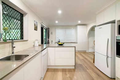 This is an example of a mid-sized transitional u-shaped separate kitchen in Brisbane with a single-bowl sink, shaker cabinets, white cabinets, quartz benchtops, multi-coloured splashback, mosaic tile splashback, stainless steel appliances, light hardwood floors, a peninsula, brown floor and brown benchtop.