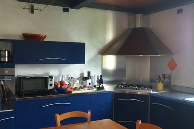 Immagine di una grande cucina a L design chiusa con lavello da incasso, ante lisce, ante blu, top in acciaio inossidabile, paraspruzzi grigio, elettrodomestici da incasso, pavimento in pietra calcarea, nessuna isola, pavimento giallo e top grigio