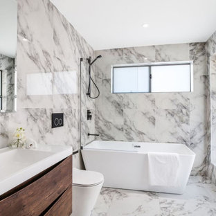 Large contemporary master bathroom in Sydney with brown cabinets, a freestanding tub, a shower/bathtub combo, a one-piece toilet, black and white tile, marble, marble floors, a drop-in sink, solid surface benchtops, a hinged shower door, white benchtops, a single vanity and a floating vanity.