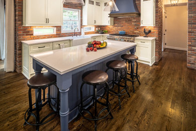 Eat-in kitchen - large french country medium tone wood floor and brown floor eat-in kitchen idea in Cincinnati with a farmhouse sink, beaded inset cabinets, white cabinets, quartz countertops, red backsplash, brick backsplash, paneled appliances, an island and white countertops