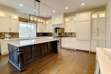 Inspiration for a large transitional u-shaped medium tone wood floor and brown floor kitchen remodel in Chicago with a farmhouse sink, raised-panel cabinets, white cabinets, marble countertops, metallic backsplash, subway tile backsplash, stainless steel appliances and an island