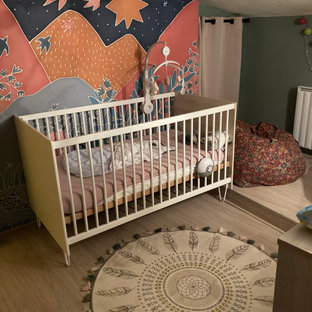 Cette image montre une petit chambre de bébé neutre avec un mur multicolore, sol en stratifié, un sol beige, un plafond en poutres apparentes et du papier peint.