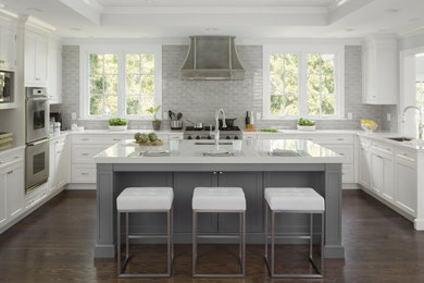 Inspiration for a large transitional u-shaped separate kitchen in New York with an undermount sink, raised-panel cabinets, white cabinets, quartz benchtops, grey splashback, ceramic splashback, stainless steel appliances, dark hardwood floors, with island, brown floor and white benchtop.