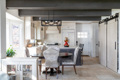 Mid-sized elegant l-shaped limestone floor, beige floor and exposed beam eat-in kitchen photo in Milwaukee with a farmhouse sink, beaded inset cabinets, distressed cabinets, quartz countertops, beige backsplash, limestone backsplash, paneled appliances, an island and white countertops