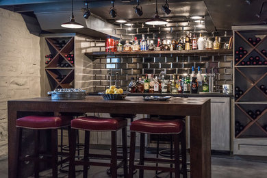 Inspiration for an industrial single-wall gray floor and concrete floor wet bar remodel in Other with shaker cabinets, black backsplash, metal backsplash and gray cabinets