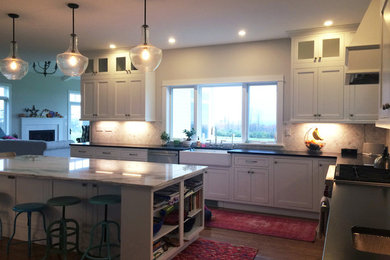 Large transitional l-shaped dark wood floor and brown floor kitchen pantry photo in Other with a farmhouse sink, recessed-panel cabinets, white cabinets, quartz countertops, beige backsplash, ceramic backsplash, stainless steel appliances, an island and black countertops