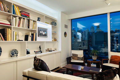 Diseño de biblioteca en casa abierta minimalista de tamaño medio sin televisor con paredes blancas, suelo de madera en tonos medios y suelo marrón