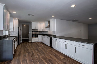 Eat-in kitchen - large contemporary galley porcelain tile eat-in kitchen idea in Phoenix with a farmhouse sink, shaker cabinets, white cabinets, quartzite countertops, white backsplash, stainless steel appliances and a peninsula