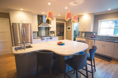 Open concept kitchen - large contemporary l-shaped medium tone wood floor open concept kitchen idea in San Francisco with an undermount sink, recessed-panel cabinets, blue cabinets, granite countertops, blue backsplash, glass tile backsplash, stainless steel appliances and an island