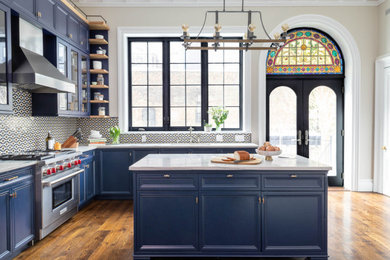 Inspiration for a large transitional l-shaped dark wood floor and brown floor kitchen remodel with an undermount sink, recessed-panel cabinets, blue cabinets, quartzite countertops, multicolored backsplash, mosaic tile backsplash, paneled appliances, an island and white countertops