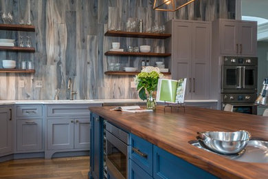 Large transitional l-shaped medium tone wood floor kitchen photo in Other with an undermount sink, shaker cabinets, blue cabinets, wood countertops, gray backsplash, stainless steel appliances, an island and gray countertops