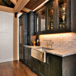 他の地域の中サイズのラスティックスタイルのおしゃれなウェットバー (アンダーカウンターシンク、落し込みパネル扉のキャビネット、黒いキャビネット、赤いキッチンパネル、レンガのキッチンパネル、無垢フローリング、ソープストーンカウンター) の写真