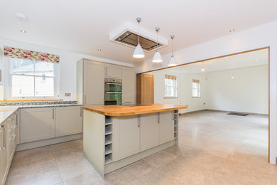 Medium sized contemporary l-shaped open plan kitchen with shaker cabinets, granite worktops, stainless steel appliances, ceramic flooring and an island.