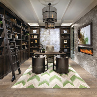 Imagen de despacho tradicional renovado con paredes grises, chimenea lineal, marco de chimenea de piedra y escritorio independiente