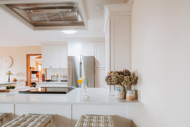 Inspiration for a small 1960s u-shaped eat-in kitchen remodel in New York with a farmhouse sink, shaker cabinets, quartz countertops, white backsplash, ceramic backsplash, stainless steel appliances and white countertops