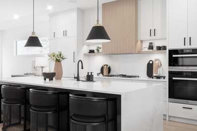 Design ideas for a large modern galley open plan kitchen with a farmhouse sink, flat-panel cabinets, grey cabinets, quartz benchtops, white splashback, engineered quartz splashback, panelled appliances, light hardwood floors, with island, brown floor and white benchtop.