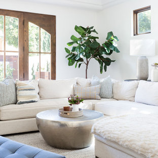 Großes, Offenes Mediterranes Wohnzimmer mit weißer Wandfarbe, braunem Holzboden, Eckkamin, Kaminsims aus Beton und Wand-TV in Los Angeles