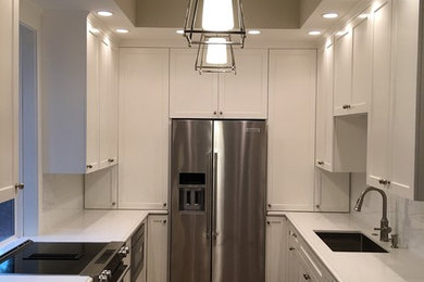 Mid-sized transitional galley terra-cotta tile and brown floor enclosed kitchen photo in Houston with an undermount sink, shaker cabinets, white cabinets, quartz countertops, white backsplash, subway tile backsplash, stainless steel appliances and a peninsula